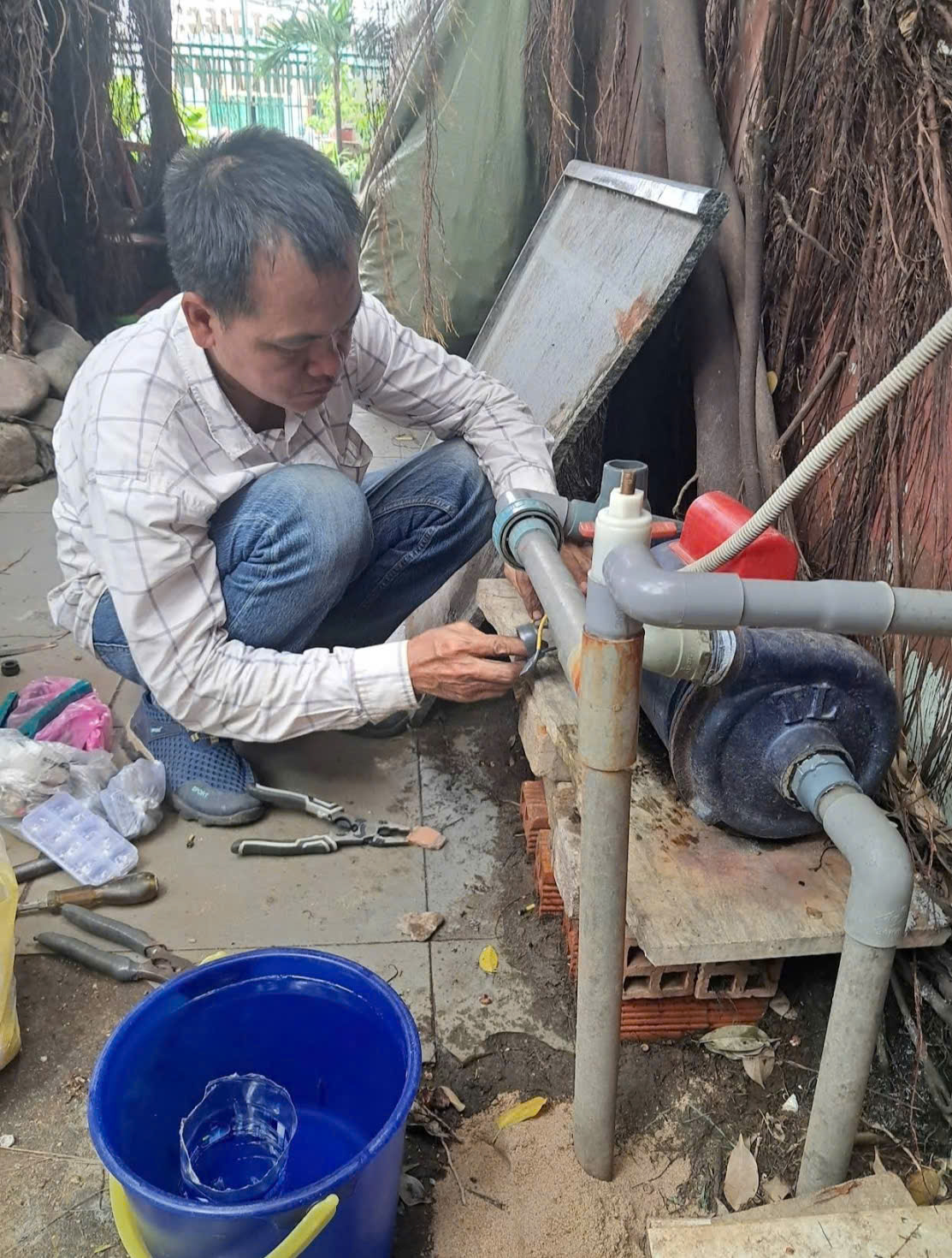 Thợ Đức Hậu kiểm tra cụm máy bơm và đường ống tại nhà dân